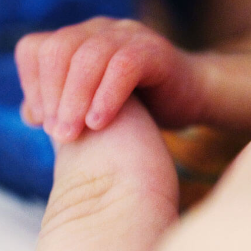 Premature baby grasps adult's thumb